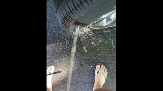 Fille publique pisse sur pneu dans un parking
