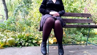 Моча с широко раздвинутыми ногами на скамейке в осеннем парке