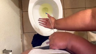 Segurando seu pênis enquanto ele mija no banheiro e brinca nele