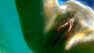 Close-up subaquático de xixi e natação nua