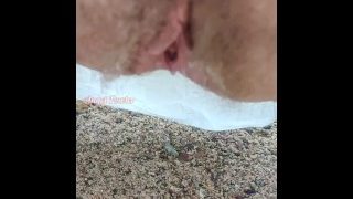 Harig poesje gepist op nat zand met omgekeerde plas en urine-opname