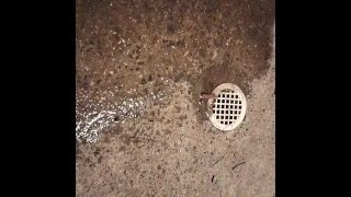 Pisser près d'un drain sur le trottoir
