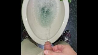 Pisser i et rent pletfrit toilet med blå rengøringsmiddel på arbejde